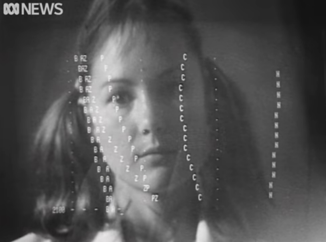 A youthful female scientist in a white lab coat with hair in bunches sits at a glass teletype, a computer display. You see only her face reflected in the display. The display is drawing an ASCII art graph at about thirty characters per second, i.e. slowly.