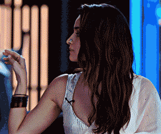 A woman elegantly gestures while wearing traditional attire.