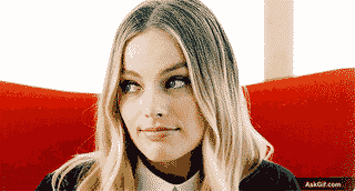 A person looks thoughtfully while seated on a red couch.