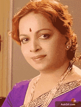 विजया निर्मला सुंदर बैंगनी साड़ी पहनकर गर्मजोशी से मुस्कुरा रही हैं