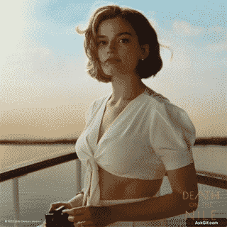 एम्मा मैकी सूर्यास्त के बैकग्राउंड में कैमरे के साथ सोचते हुए पोज़ देती हैं