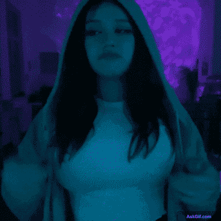 A girl in a hoodie displays a contemplative expression in neon light.