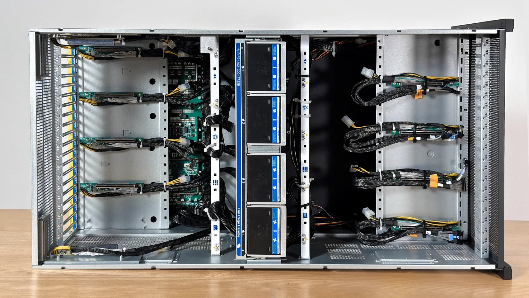 Top-down — the PCIe adapter boards, the center fan wall, and the MCIO cabling
