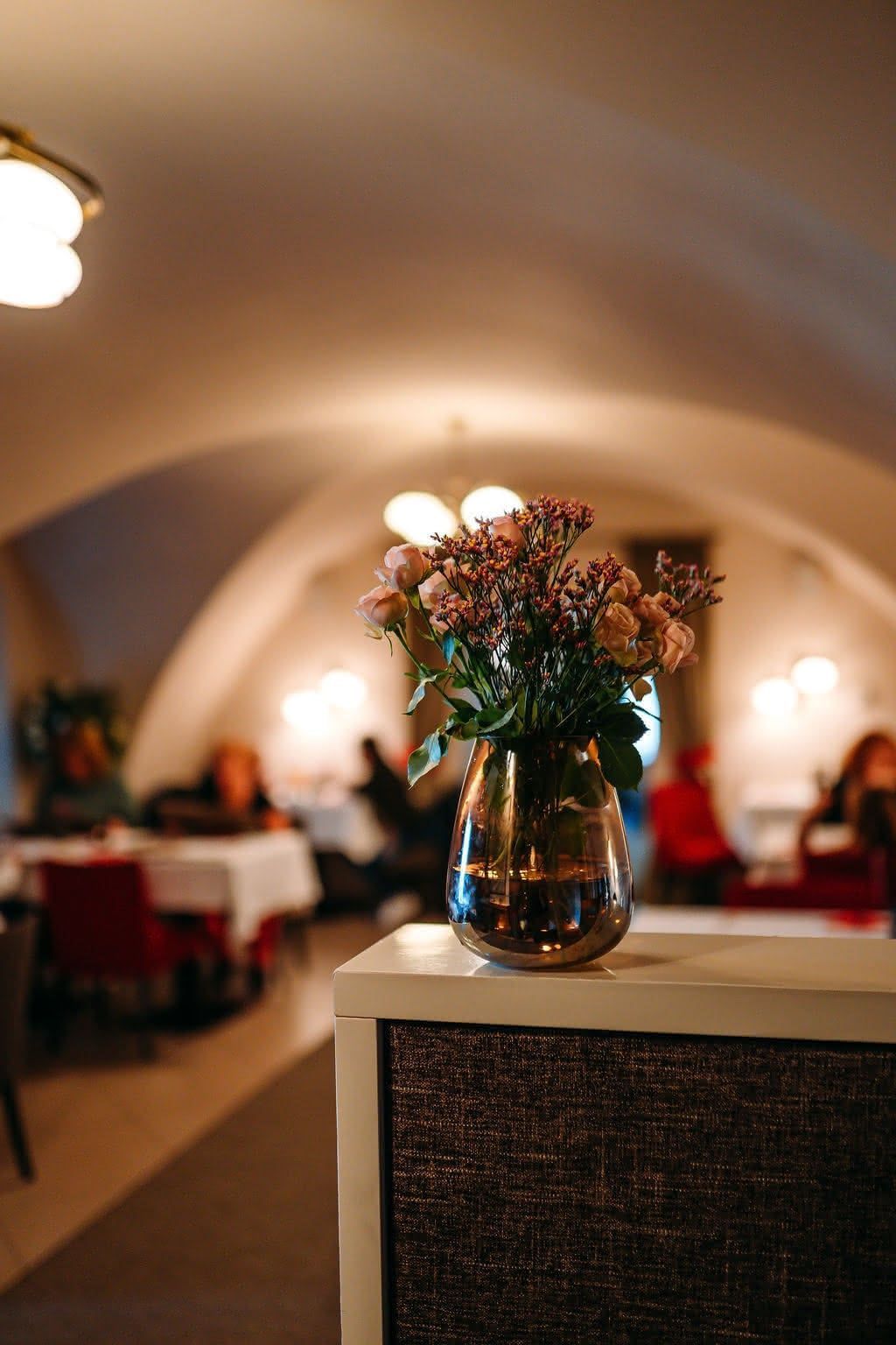 Restaurace — květiny a hosté v pozadí