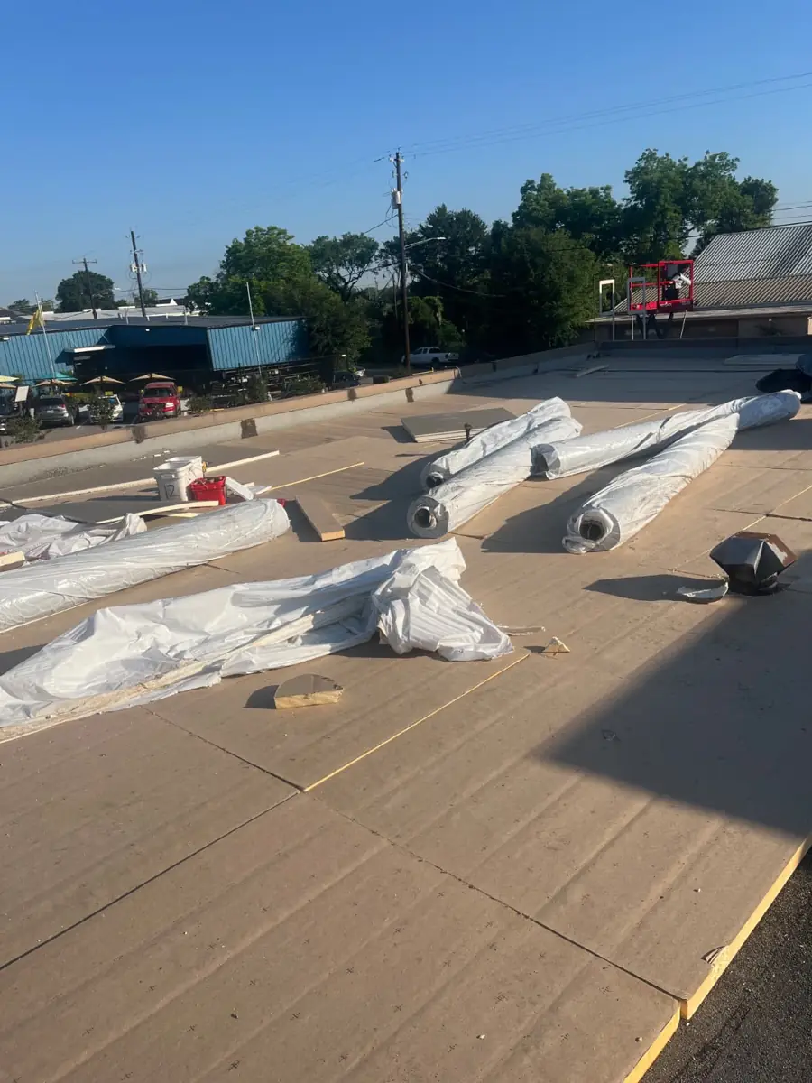 Commercial roof tear-off with new cover board and underlayment in progress