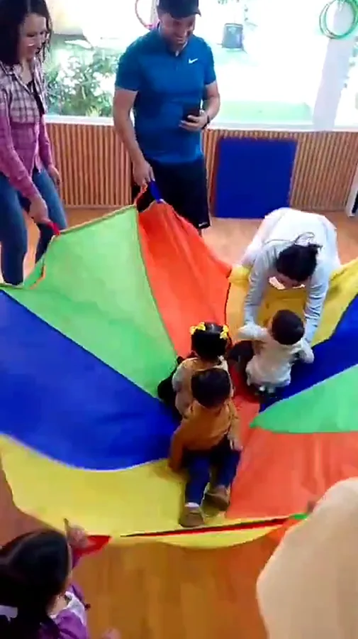 Peques y familias jugando con un paracaídas de colores