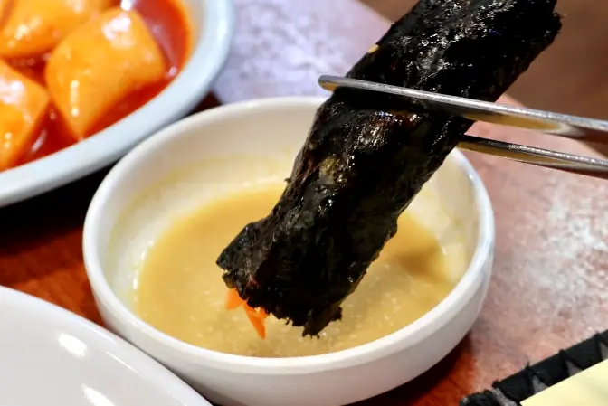 Dipping mini gimbap in mustard sauce