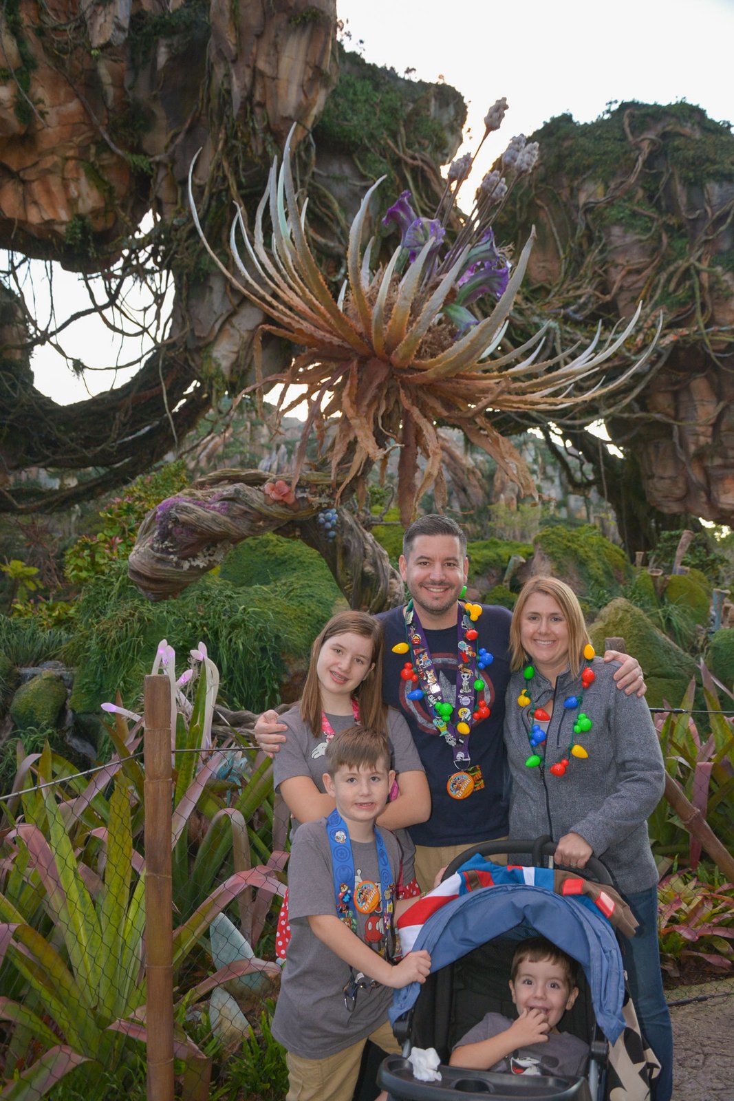 A family poses beneath the floating mountains and a towering alien plant in Pandora — The World of Avatar at Disney's Animal Kingdom, surrounded by the land's lush, otherworldly landscaping.