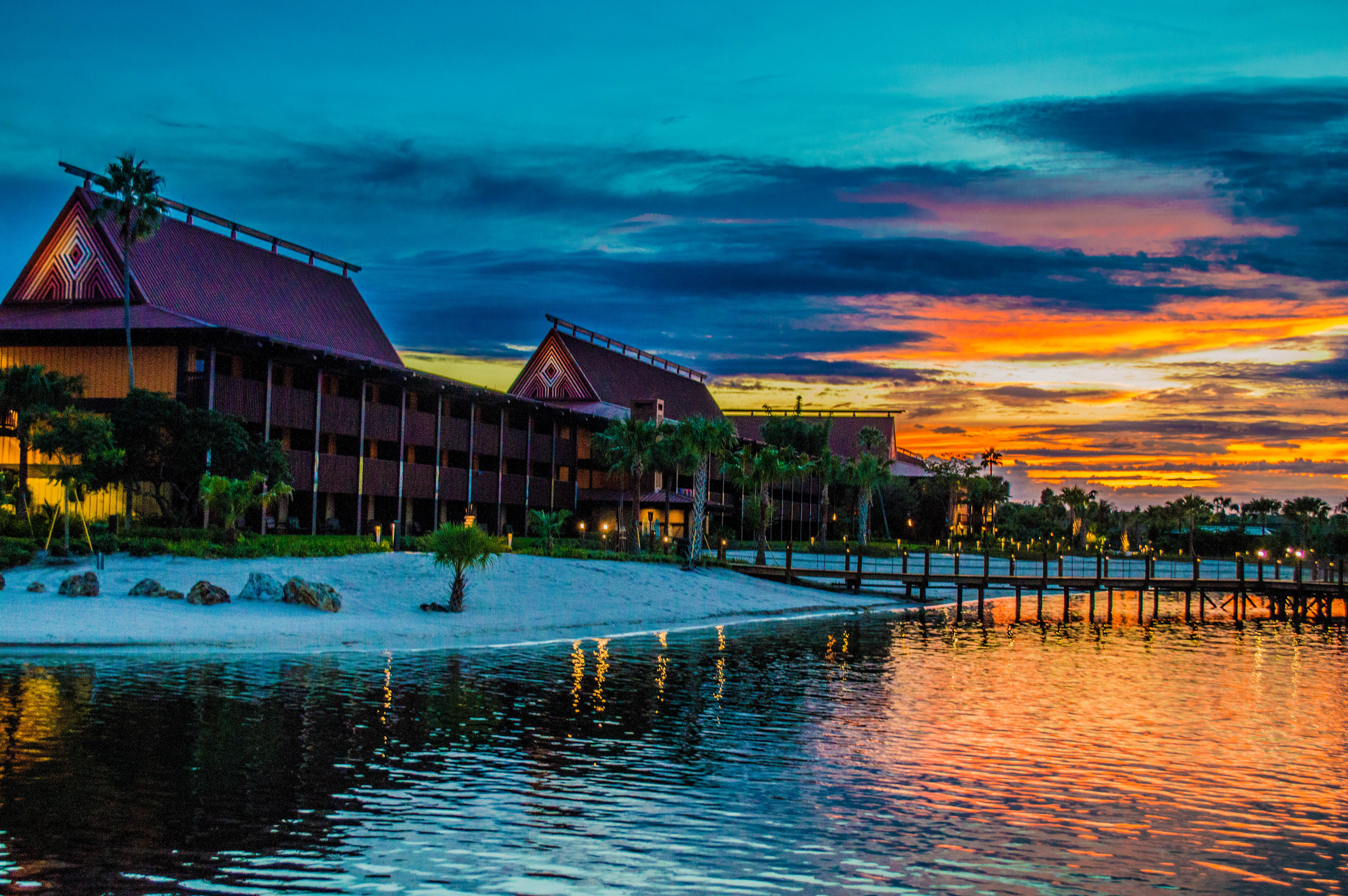 Disney's Polynesian Village Resort longhouses along the beach at sunset on Seven Seas Lagoon.