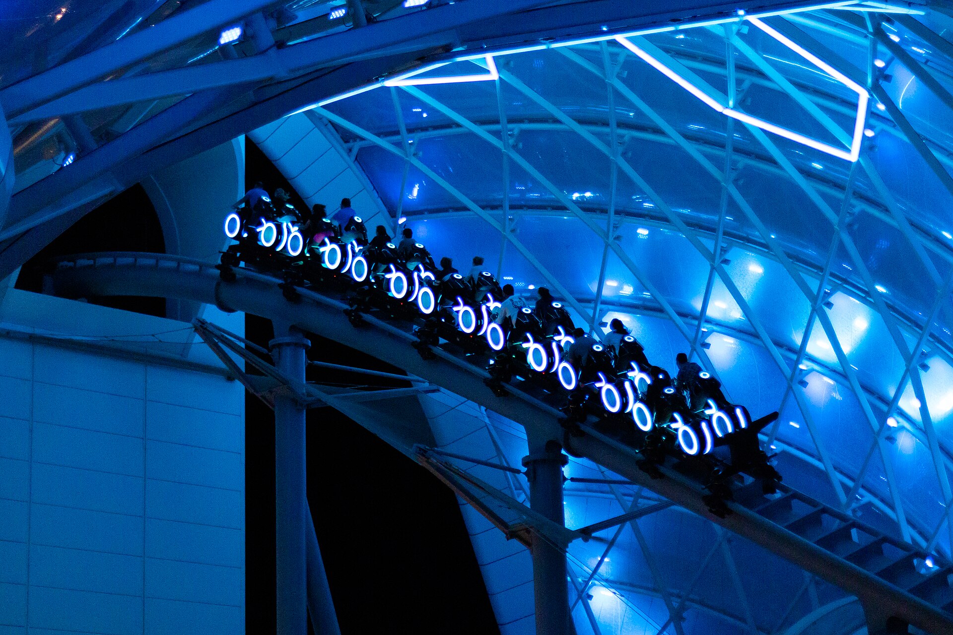 The TRON Lightcycle / Run train glows under its canopy at night in Tomorrowland at Magic Kingdom, Walt Disney World.