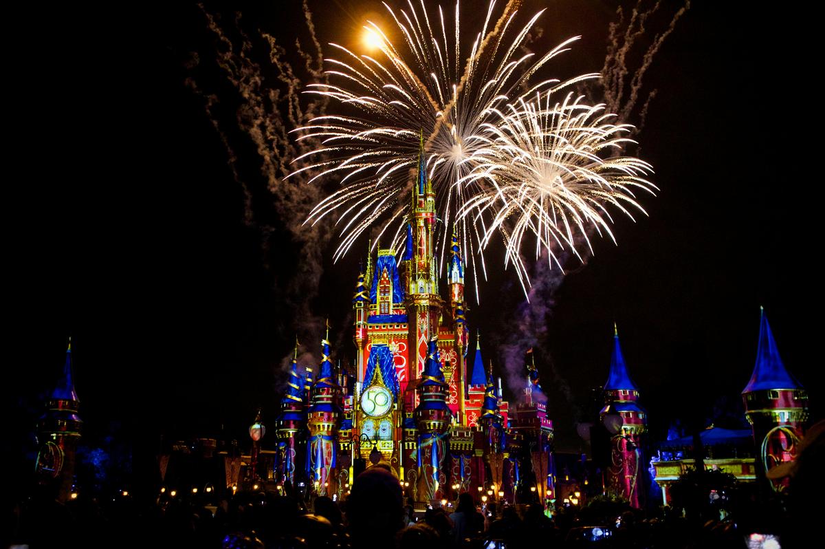 Cinderella Castle at Magic Kingdom lit with colorful projections and fireworks during the 50th anniversary celebration