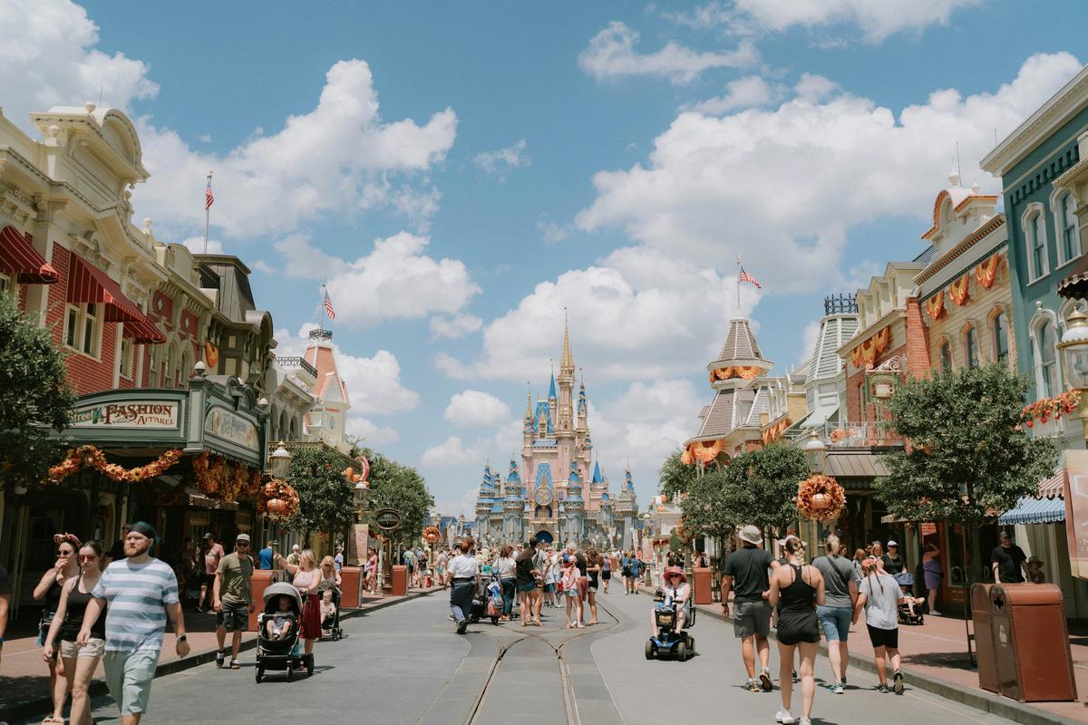 Families walking down Main Street USA at Magic Kingdom toward Cinderella Castle on a sunny day