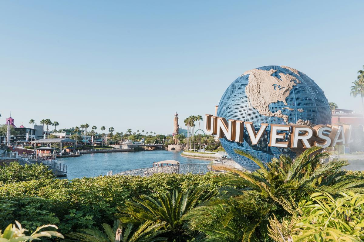 Universal Orlando globe sign with the resort waterway and palm trees on a sunny day