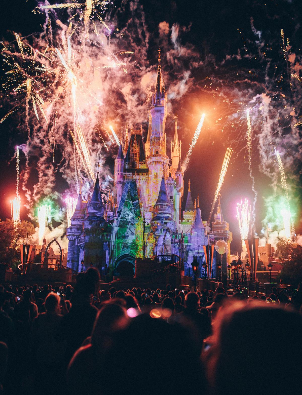 Cinderella Castle at Magic Kingdom lit up with colorful fireworks during the nighttime spectacular