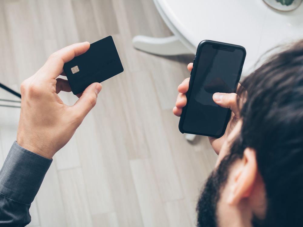 Man holding a smartphone and a credit card, making an online payment