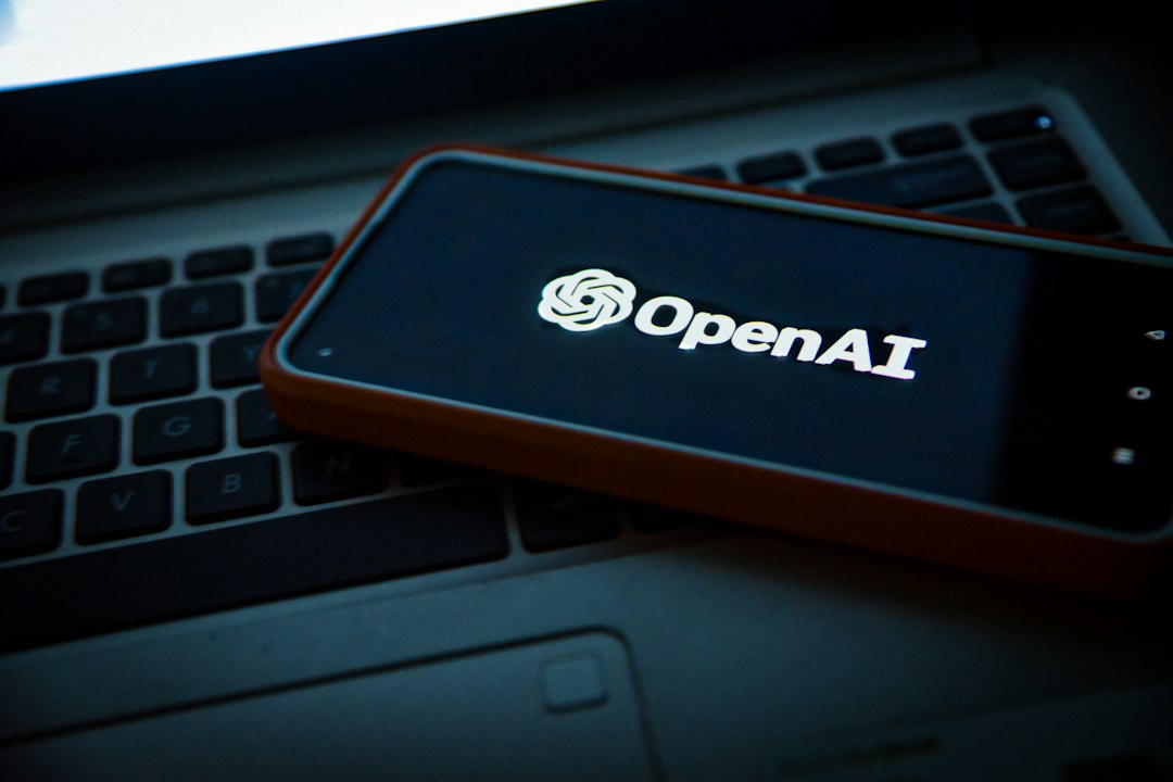 A smartphone showing the OpenAI logo on top of a laptop