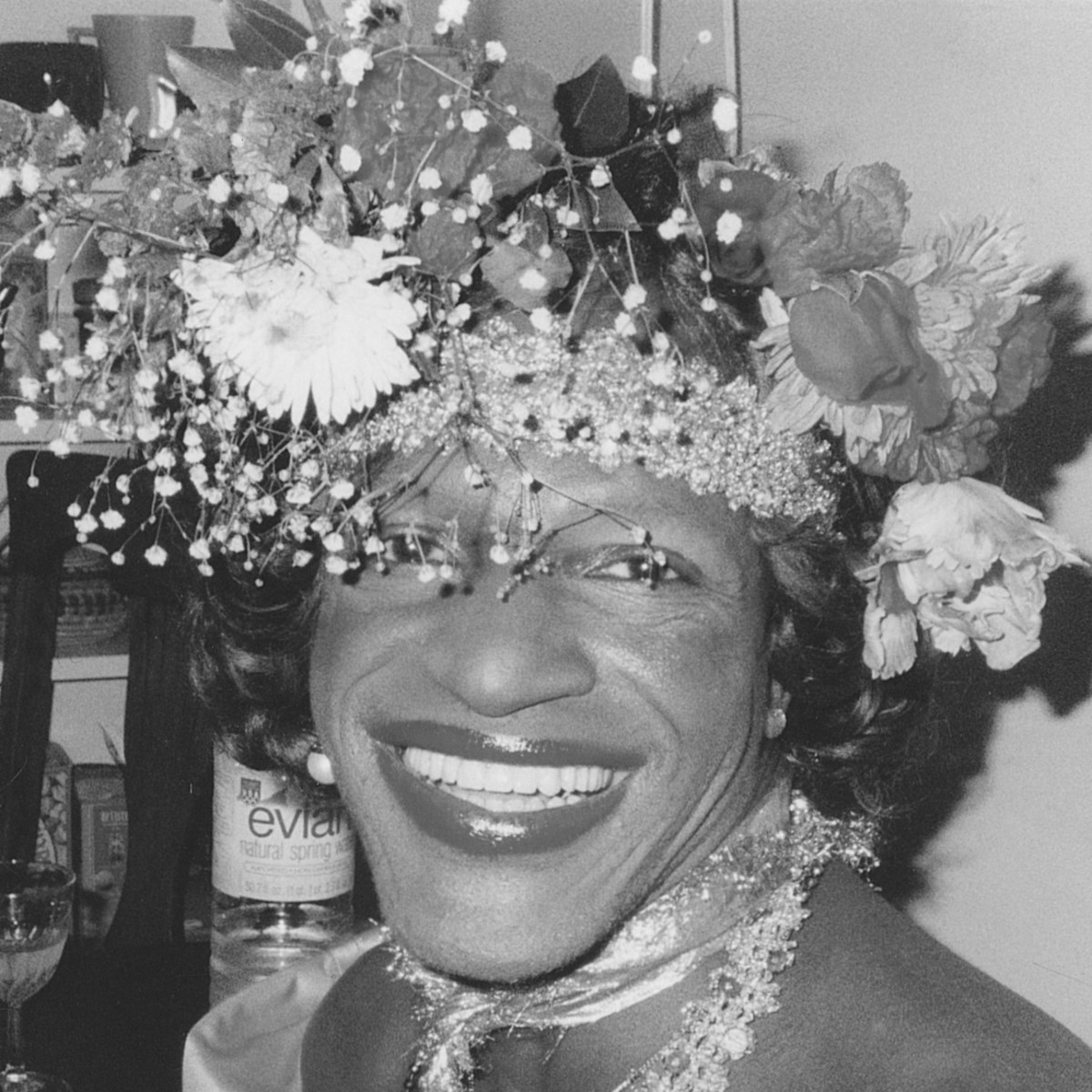 An image of a Black transgender woman with flowers in her hair and a large smile.