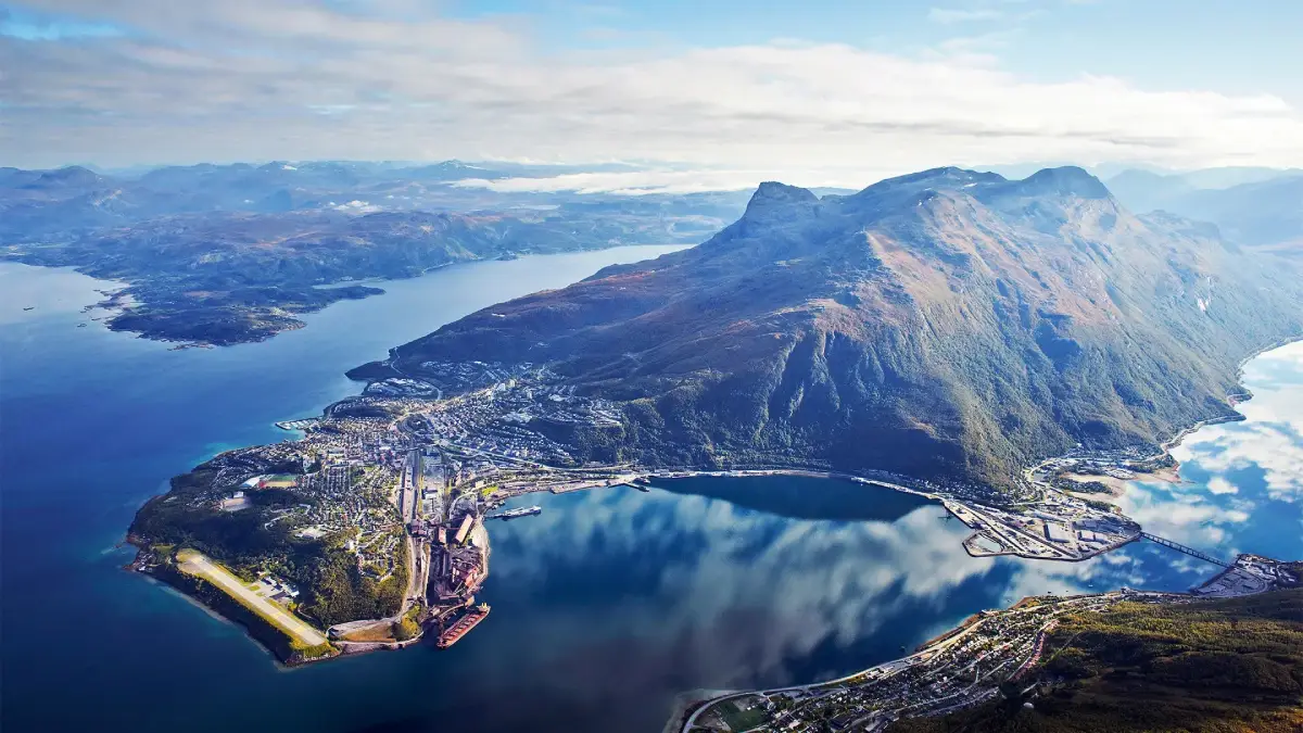 An arial view onto the city of Narvik, showing the town to the left and the mountains to the right.