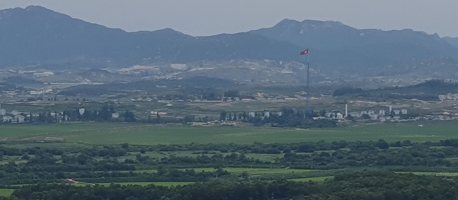 View from the Dora observatory onto North Korea. In the front, trees are visible which are within the demilitarised zone. Beyond that, a clear lack of trees is visible.