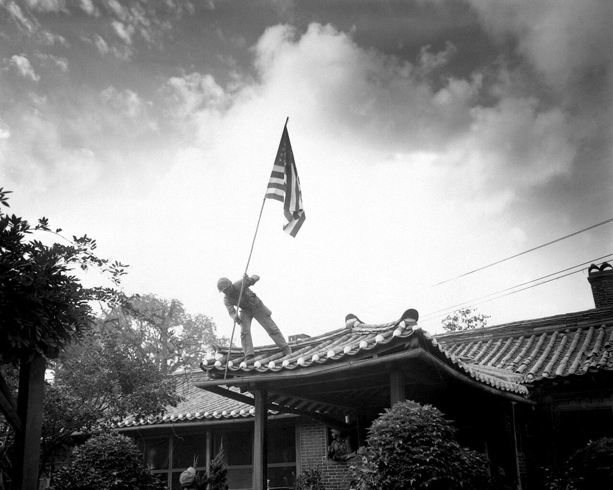 Marine Pfc. Luther Leguire raises the U.S. flag at the American consulate in Seoul as fighting rages, September 27, 1950