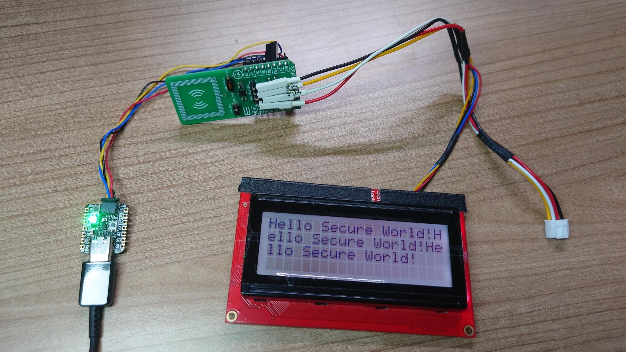 An Adafruit QtPy RP2040, a NXP SE051 and a SparkFun SerLCD wired together displaying a hello-message on the LCD