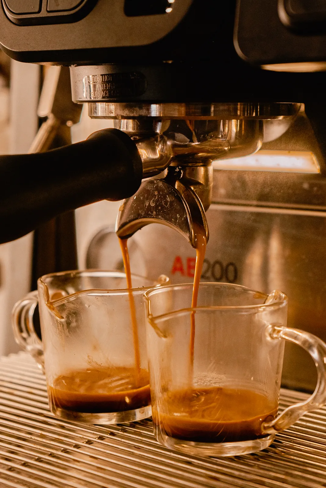 Two espresso shots pouring from the machine into glass cups inside the Common Tides trailer