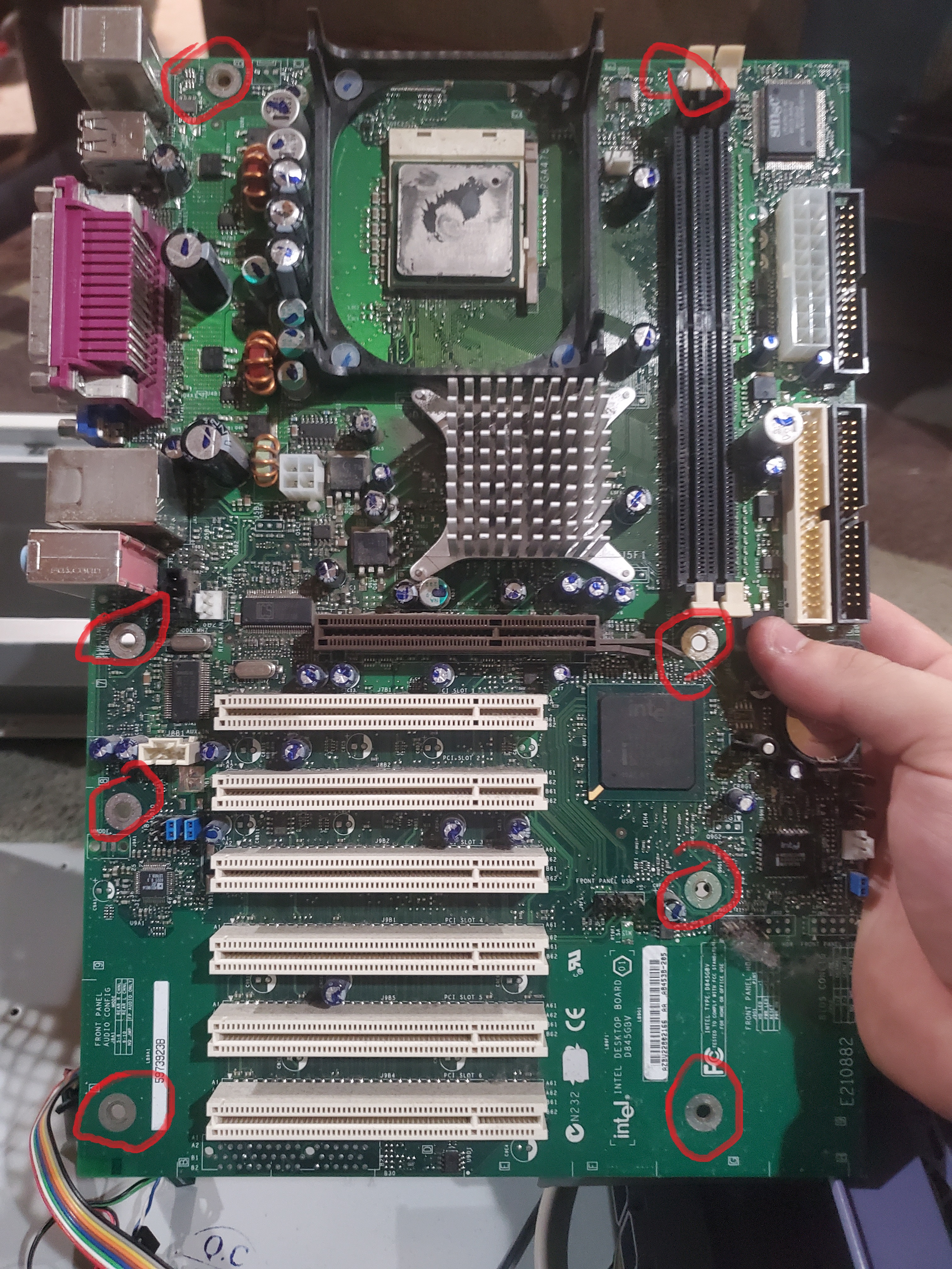 A motherboard not in the case with the anchor holes circled