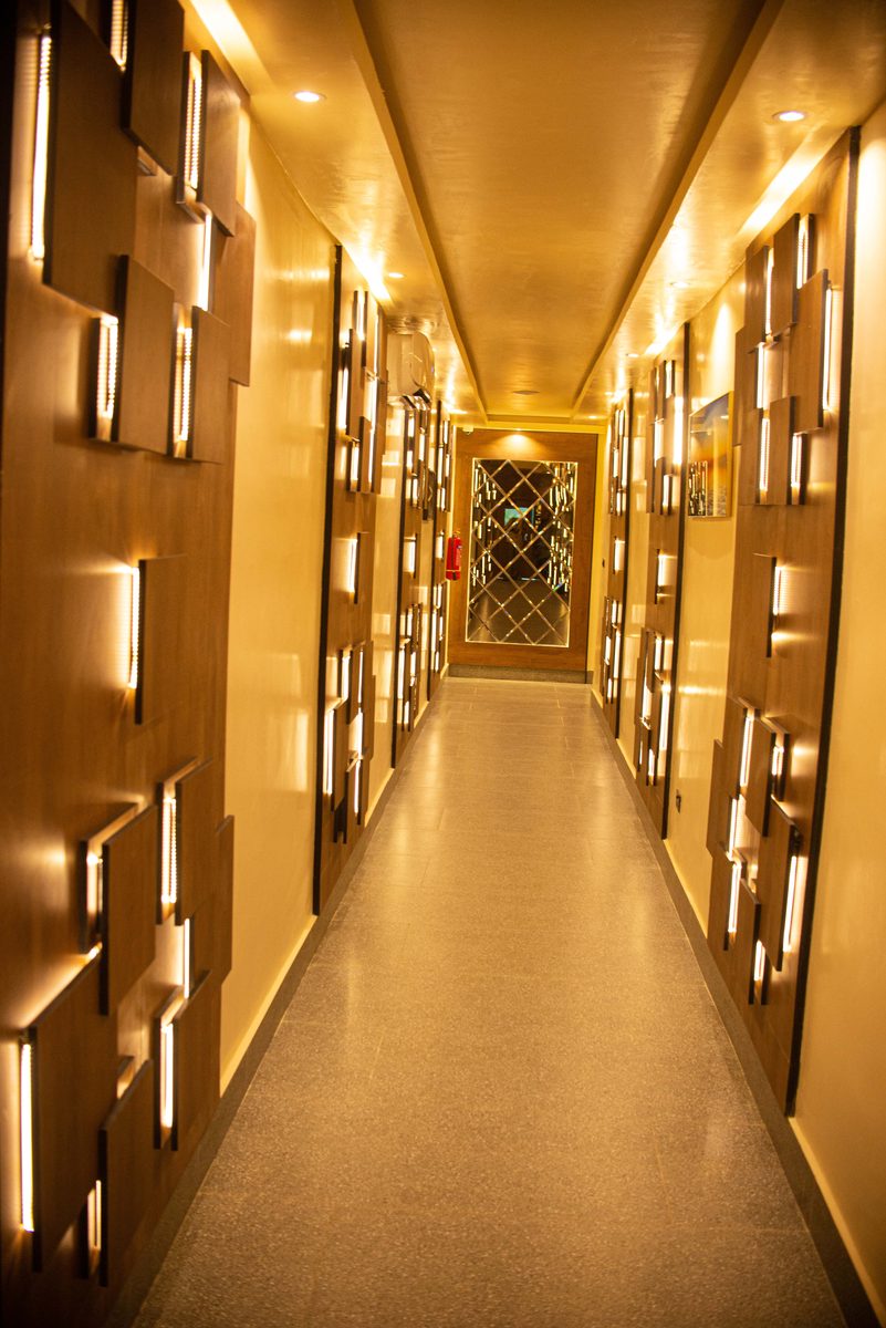 The Golden Corridor at Frank N Hotels Royal — amber-lit hallway with geometric wood panel walls