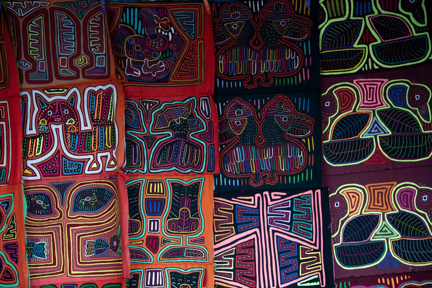 Mola panels sewn by Guna women: layered red, orange, black and purple cloth, cut to reveal bright bands of colour in the shapes of birds, animals and geometric figures