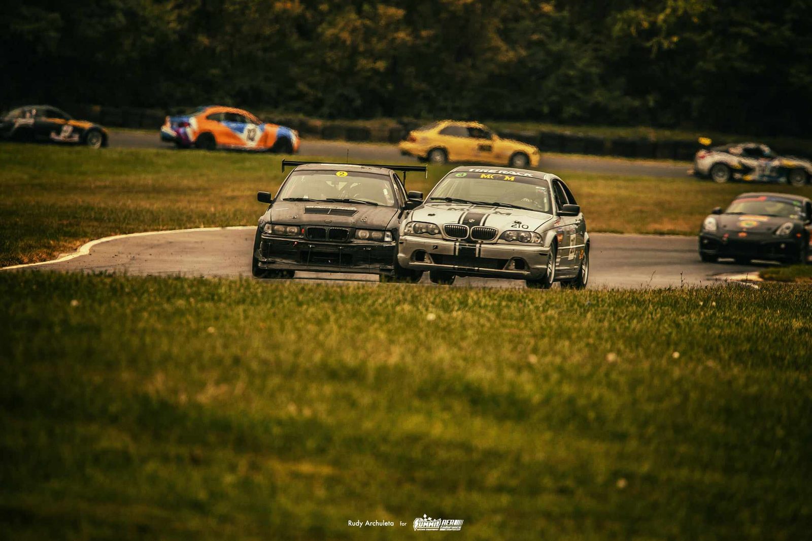 Two BMW E46 race cars nose to nose on track during ChampCar endurance racing