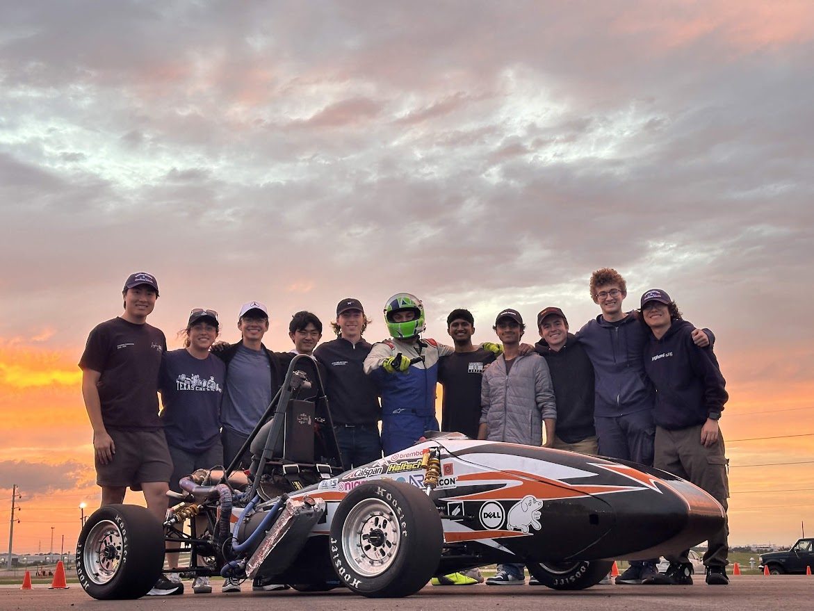 Longhorn Racing team posing with the Formula SAE car at sunset