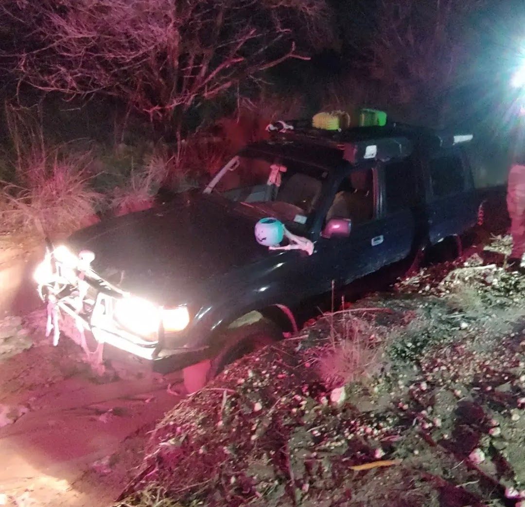 Toyota Land Cruiser navigating a muddy trail at night with headlights on