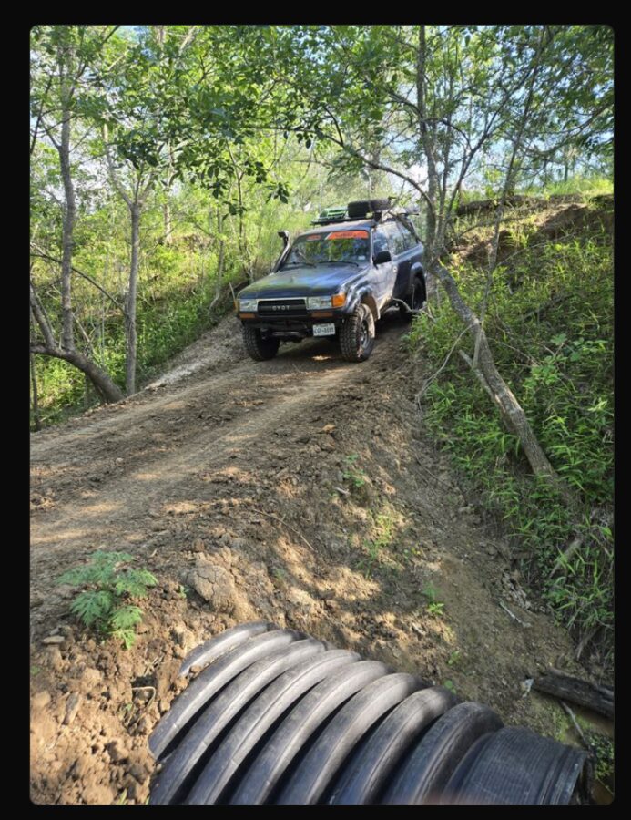 Toyota Land Cruiser on a muddy off-road trail crossing