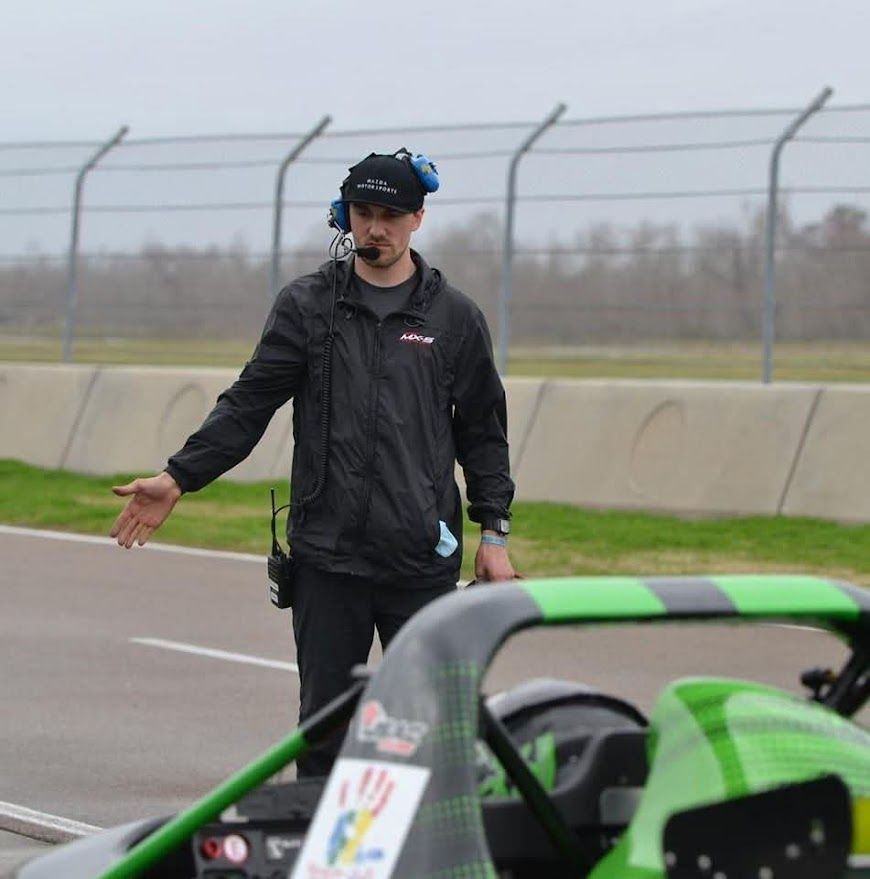 Ben directing a car on pit lane wearing a headset
