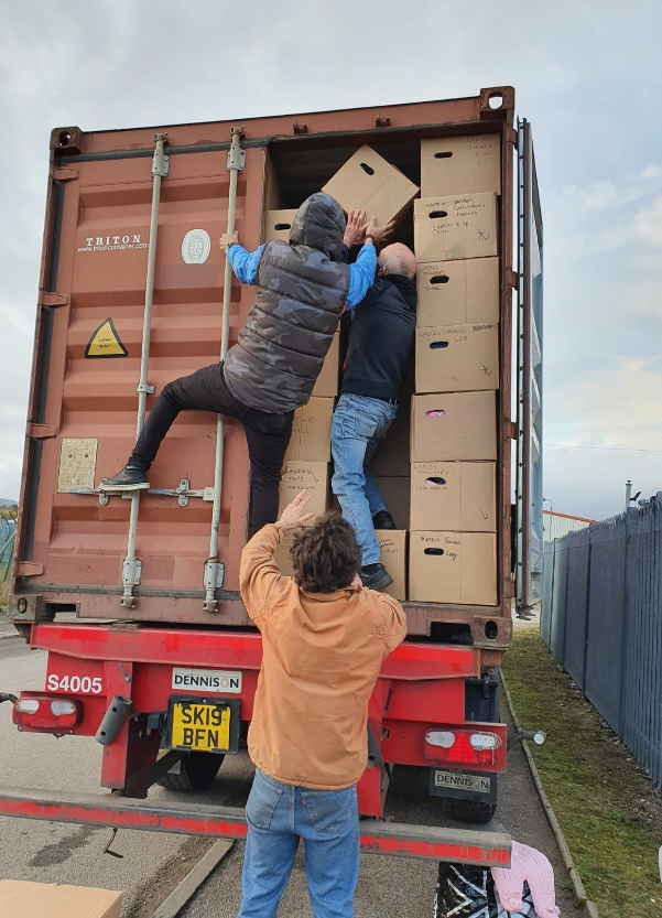 two people loading boxes into a container