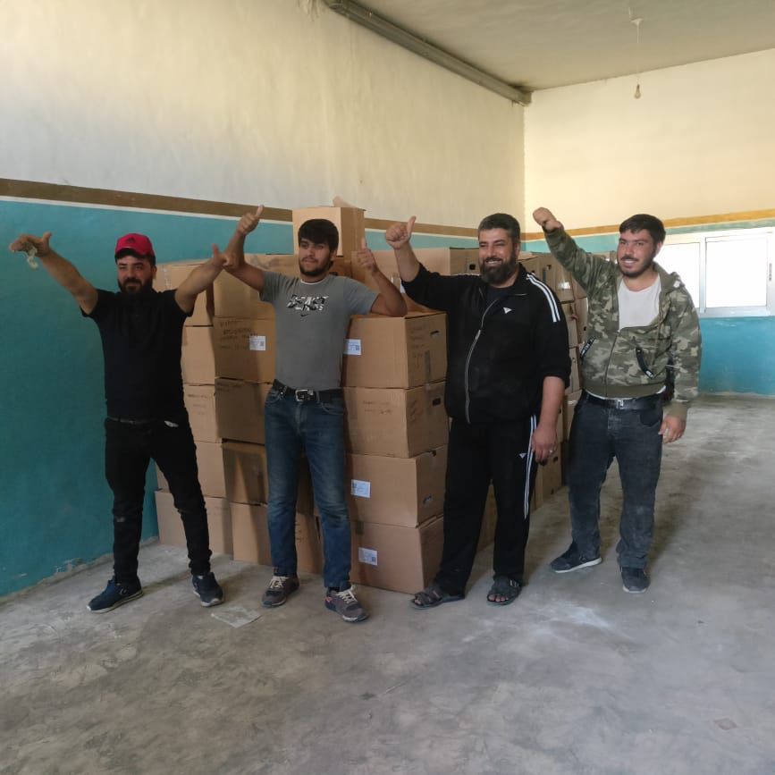 volunteers standing next to rows of boxes posing for a photo