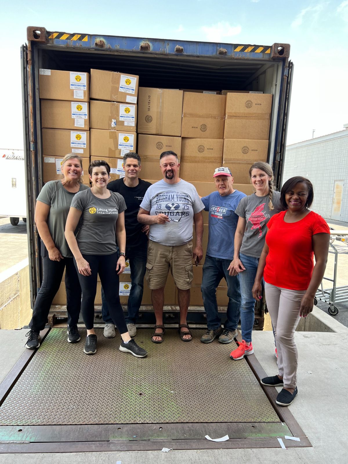 volunteers standing next to a truck they have filled to full capacity with boxes of donated items, posing for a photo