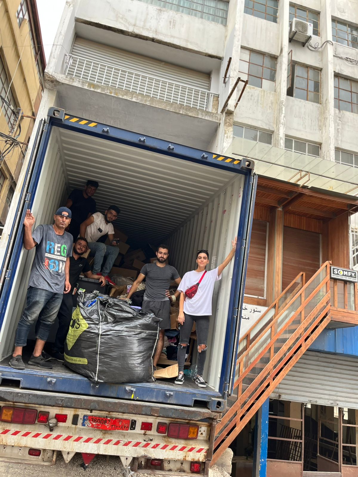 A group of people posing for a group picture inside a truck they have unloaded of humanitarian aid