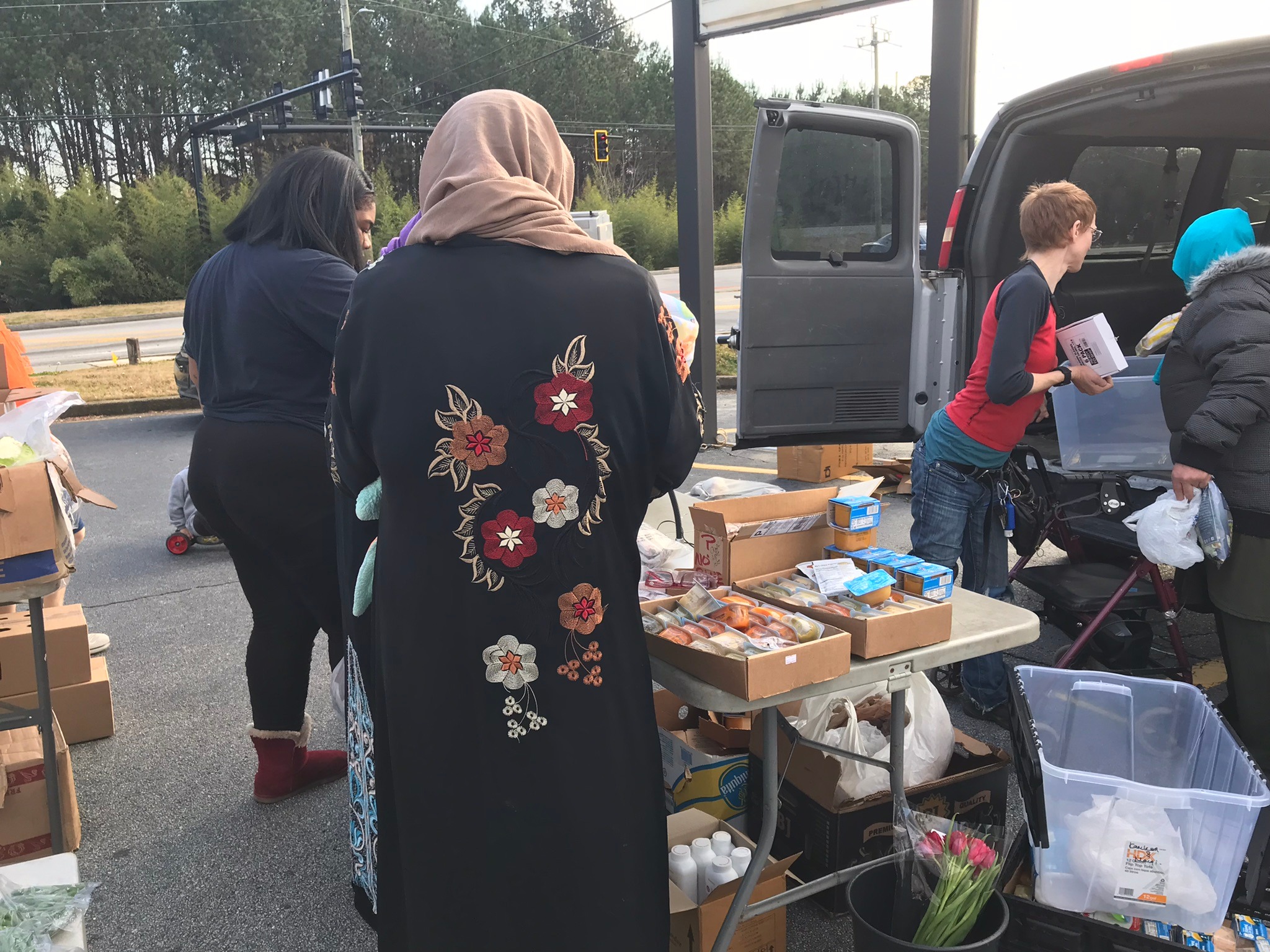 volunteers distributing donations on a table set up next to a car