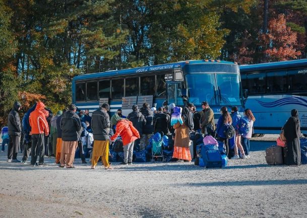 individuals and children with luggage waiting to get on a bus