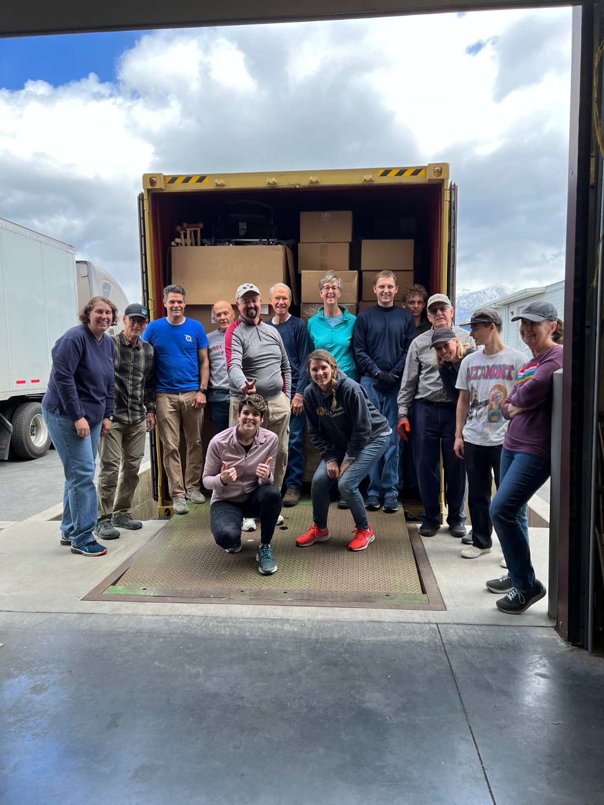 a team of volunteers posing next to a truck of donations they have loaded