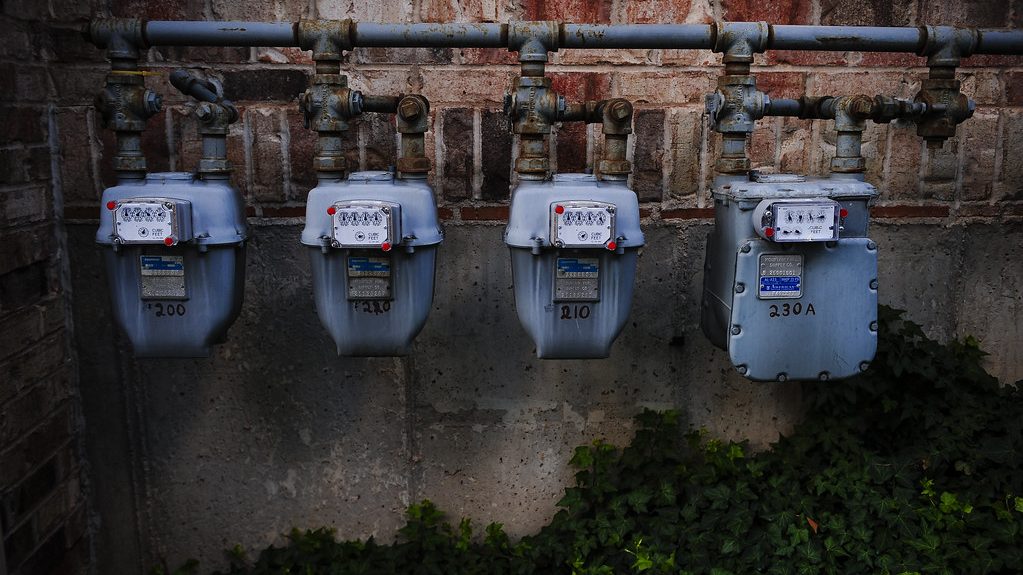 Row of residential natural gas meters mounted on a brick wall