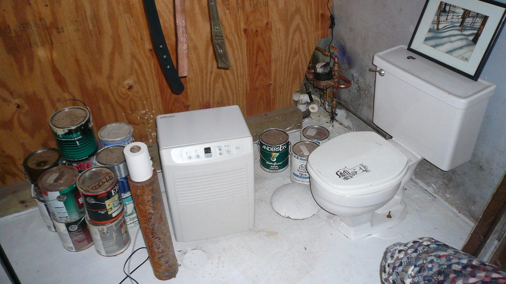 Portable dehumidifier running on the floor of an unfinished basement