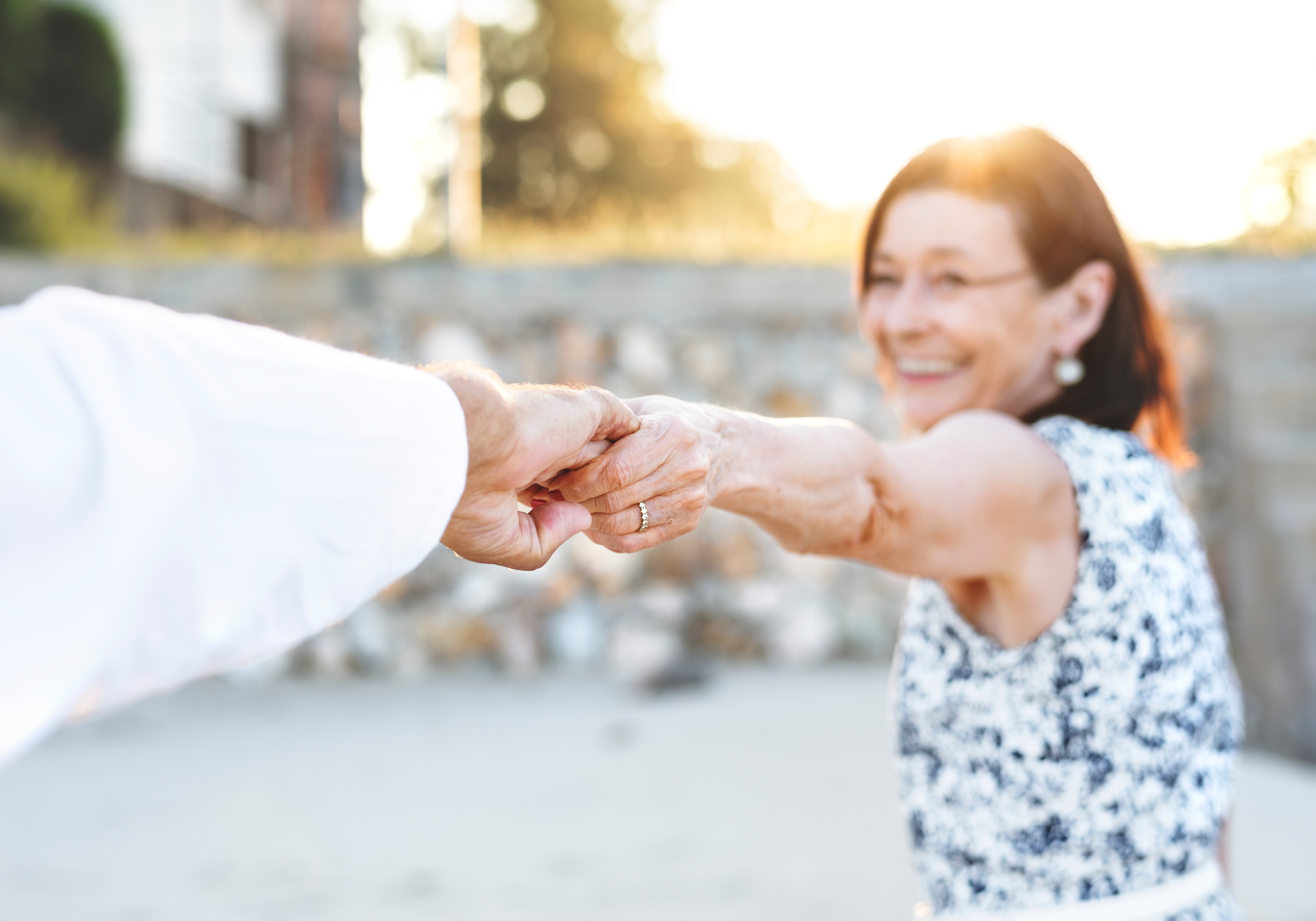 senior woman holding a friend's hand behind the camera