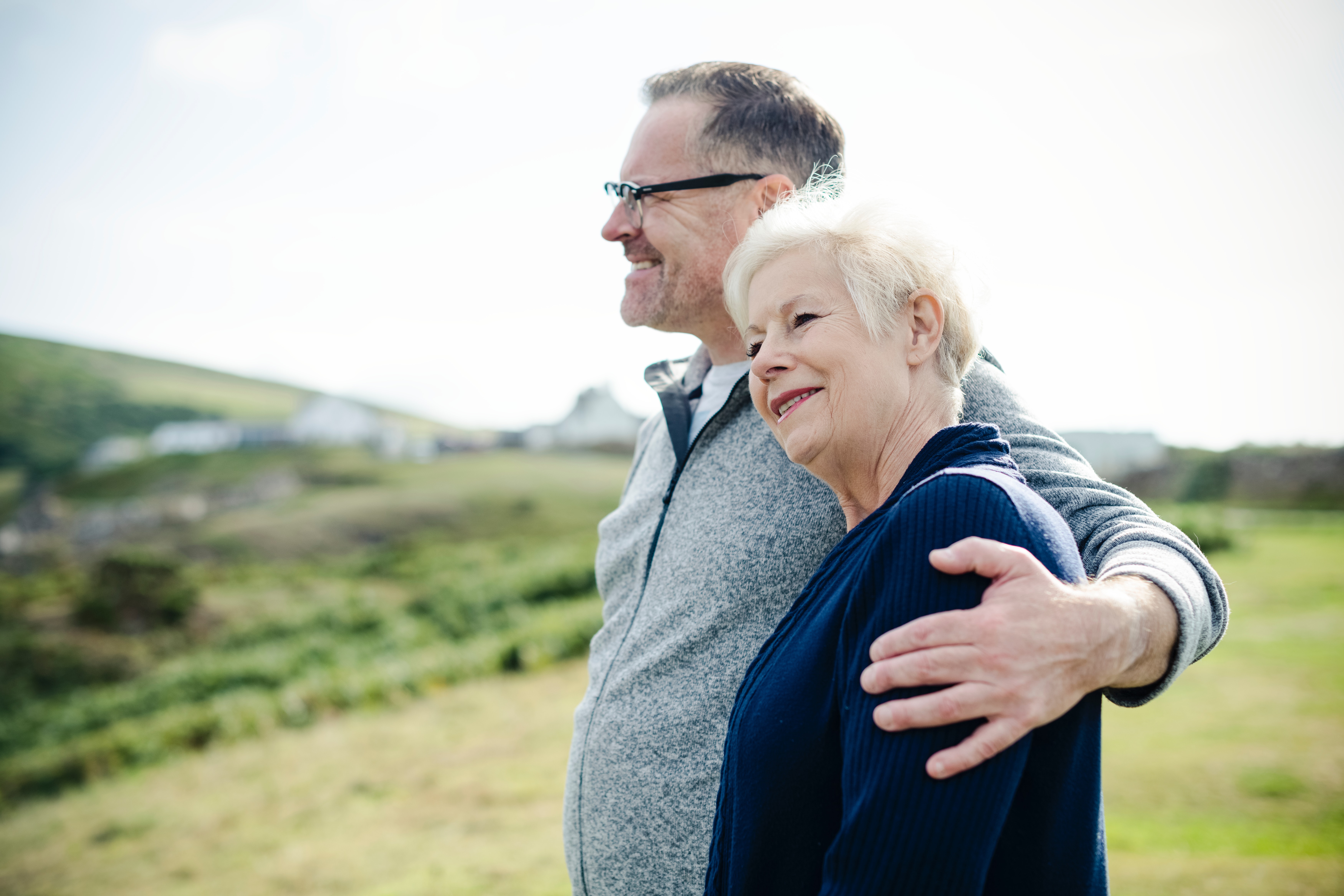 senior couple standing on a green hill