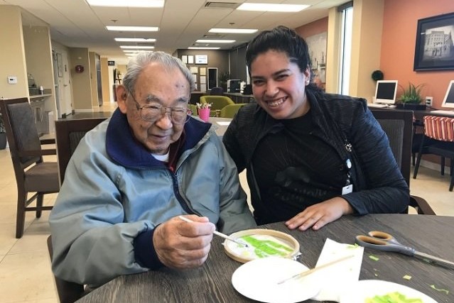 a senior and a caregiver eating a meal together 