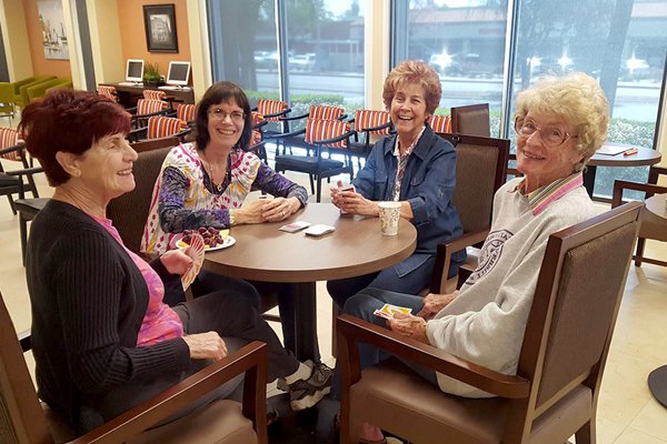 a group of senior women sitting around a table playing uno