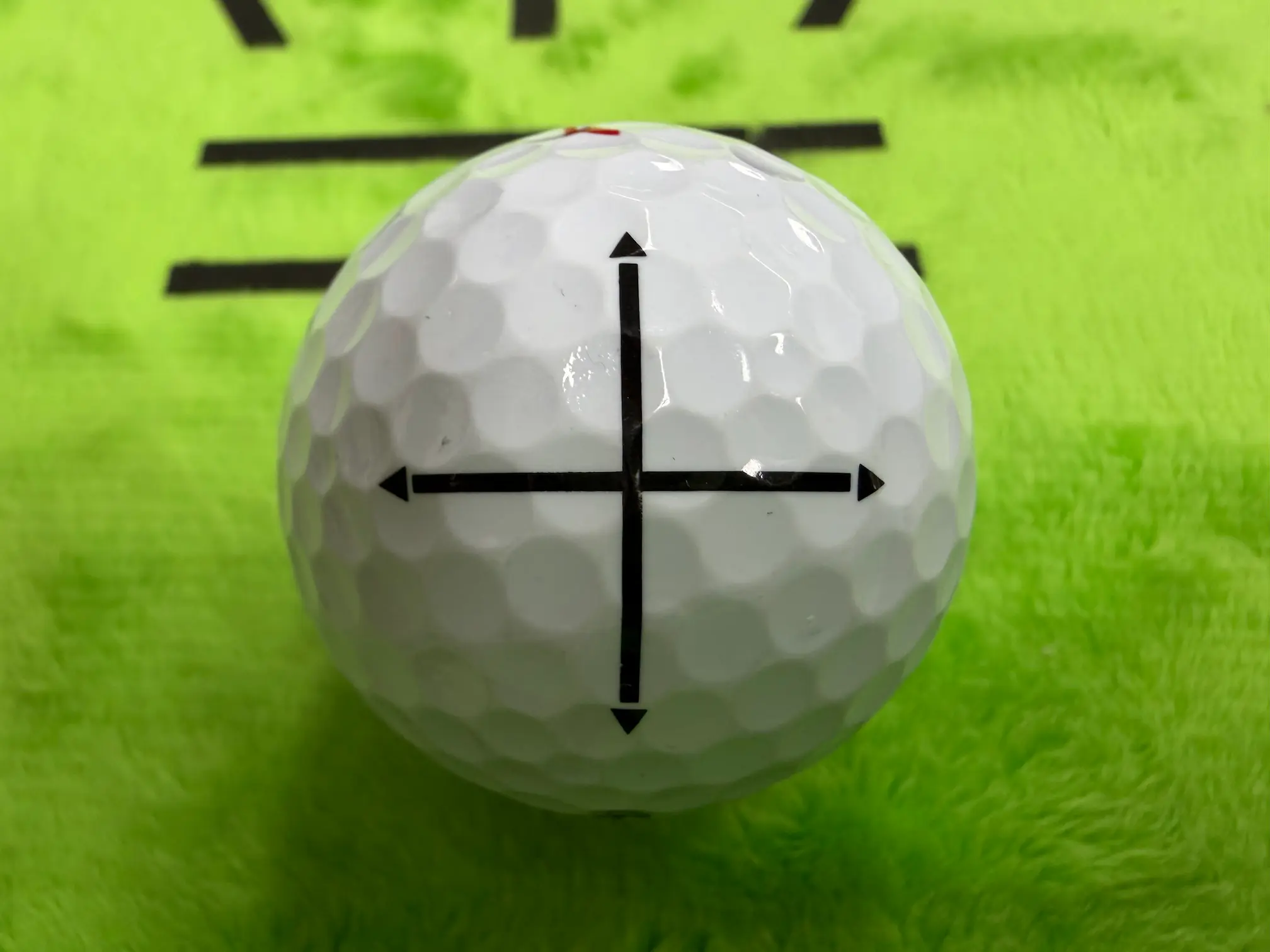 골프공 표면에 검은색 십자 모양으로 인쇄된 퍼팅 정렬 라인 사진, 가로세로 축 정렬을 동시에 돕습니다.