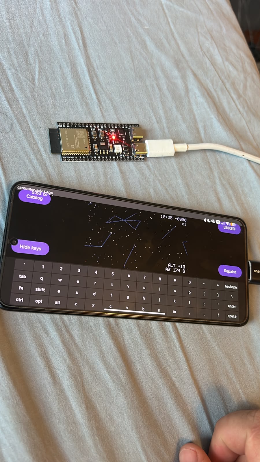 a bare ESP32-S3 devkit on an OTG cable, the phone showing the star map