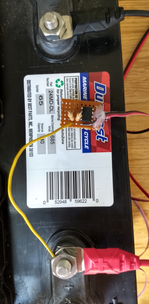 A custom home-made circuit on perfboard, with a DIP-8 microcontroller, two resistors, and some wires held on with hot glue.